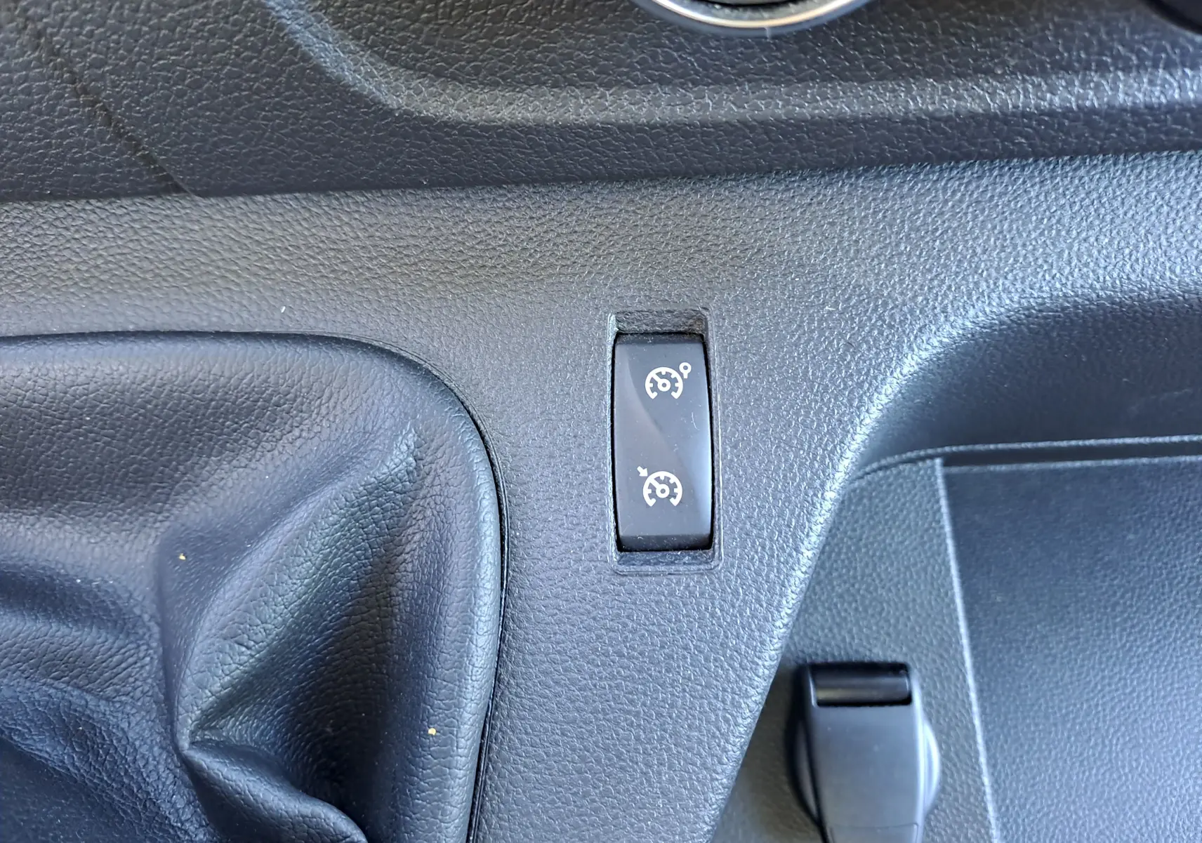 Gros plan sur le tableau de bord noir du Nissan Interstar 2024, montrant le bouton de régulateur de vitesse près du levier de vitesses.