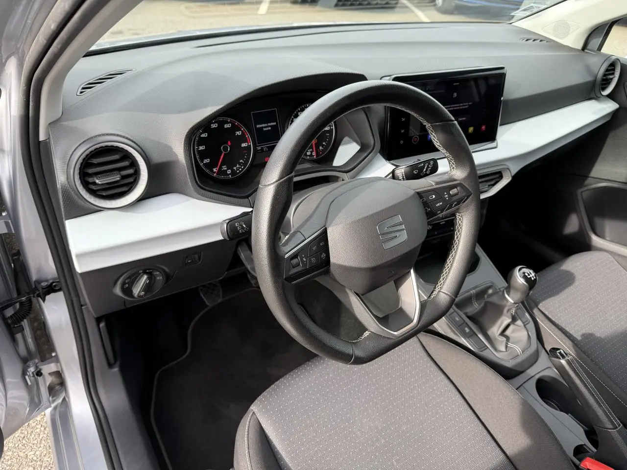 Vue intérieure côté conducteur de la SEAT Ibiza 2022 argent Urban avec tableau de bord moderne et boîte manuelle.