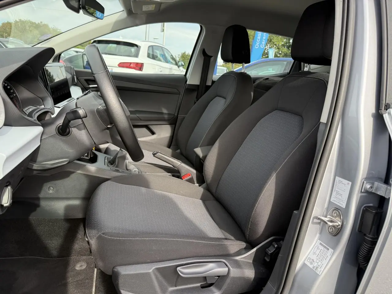 Intérieur avant droit d'une SEAT Ibiza 1.0 TSI Style argent Urban, sièges tissu noir et tableau de bord moderne.