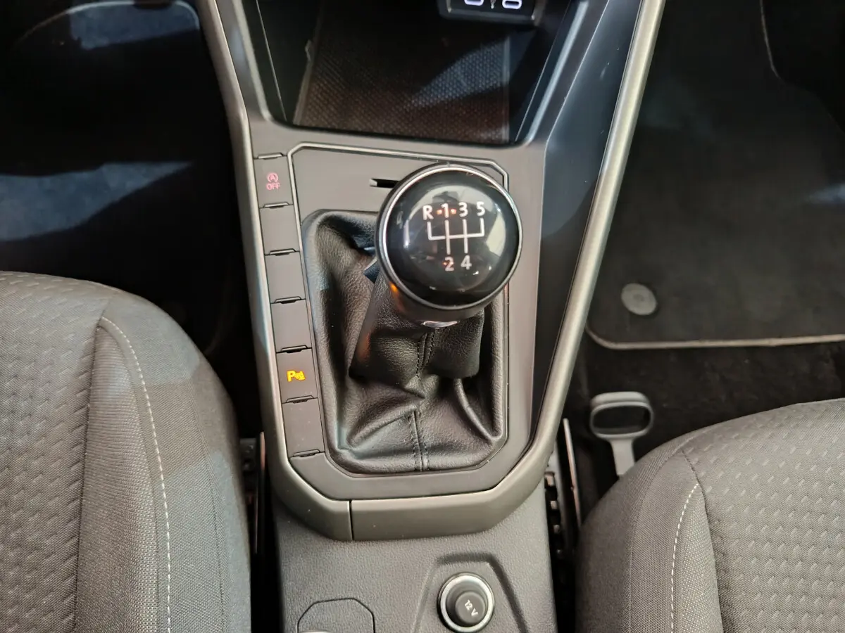 Le levier de vitesses manuel noir de la Volkswagen Polo 2020, vu de dessus entre les sièges avant gris.