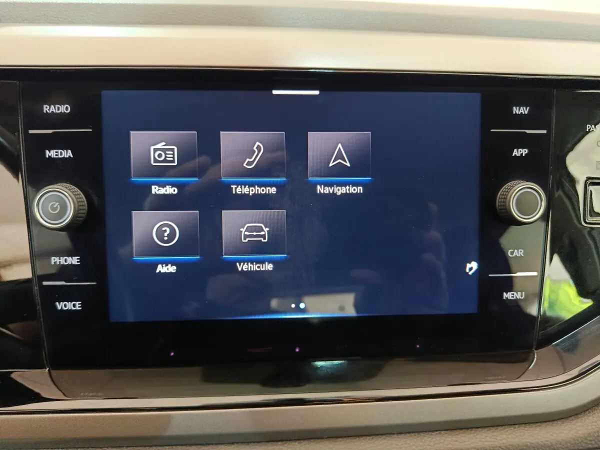 Écran tactile central affichant les options radio, téléphone, navigation et véhicule dans un Volkswagen Polo blanc de 2020.