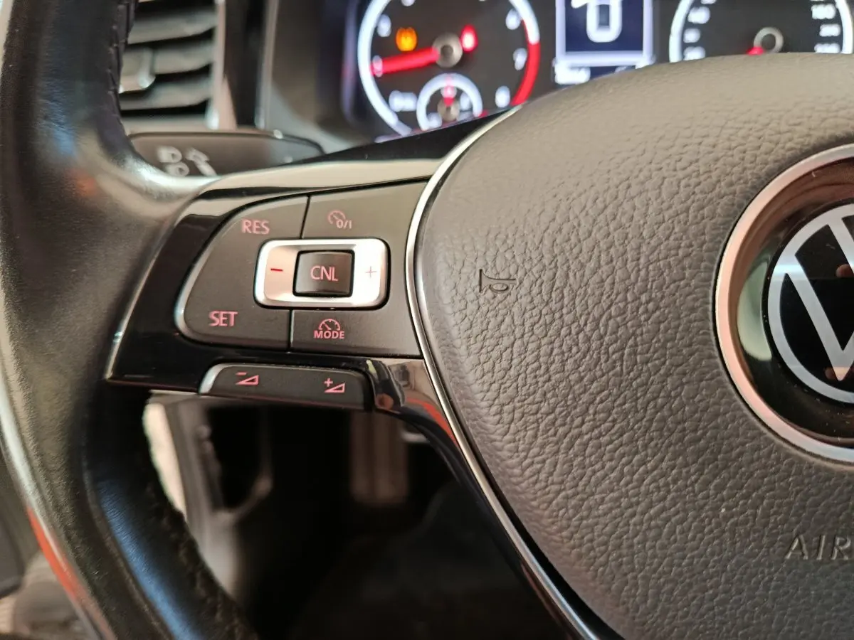 Gros plan sur le volant cuir noir de la Volkswagen Polo 2020 avec commandes de régulateur de vitesse et logo VW central.