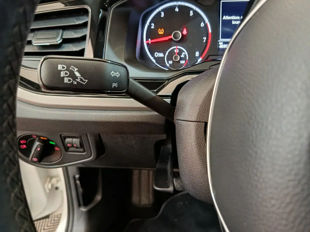 Gros plan sur le tableau de bord et le volant de la Volkswagen Polo blanche, avec indicateurs et commandes visibles.