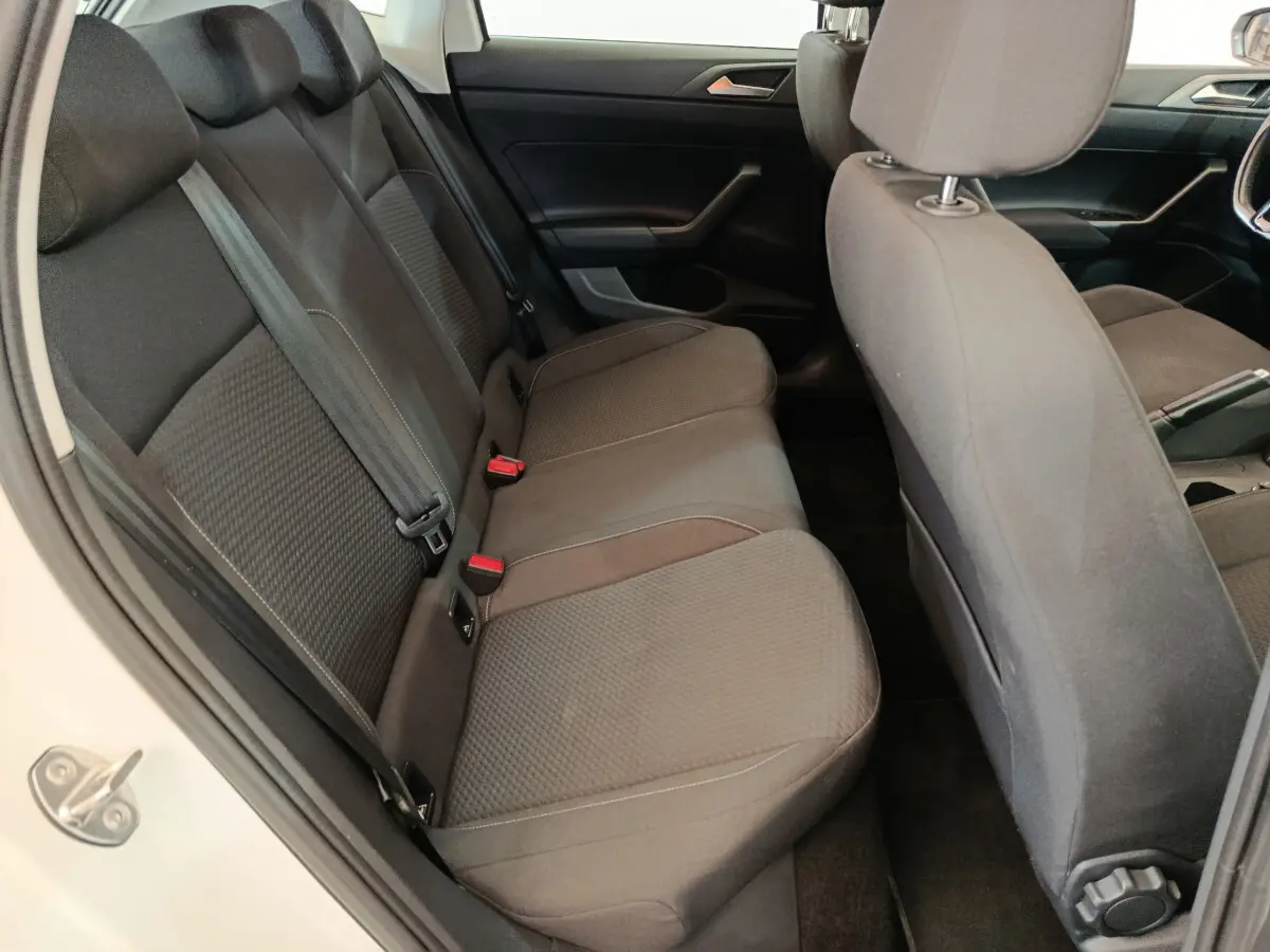 Vue intérieure côté gauche montrant la banquette arrière grise et les sièges avant d'une Volkswagen Polo blanche 2020.