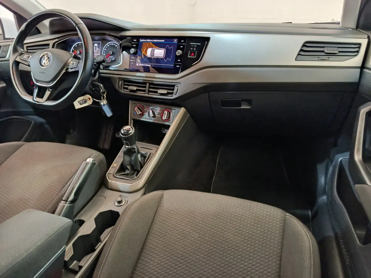 Intérieur de Volkswagen Polo 2020 essence, vue du poste de conduite avec volant cuir, boîte manuelle et écran tactile central.