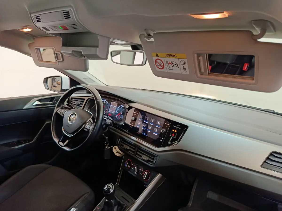 Intérieur avant droit de la Volkswagen Polo blanche 2020, tableau de bord avec écran tactile et volant cuir multifonctions.
