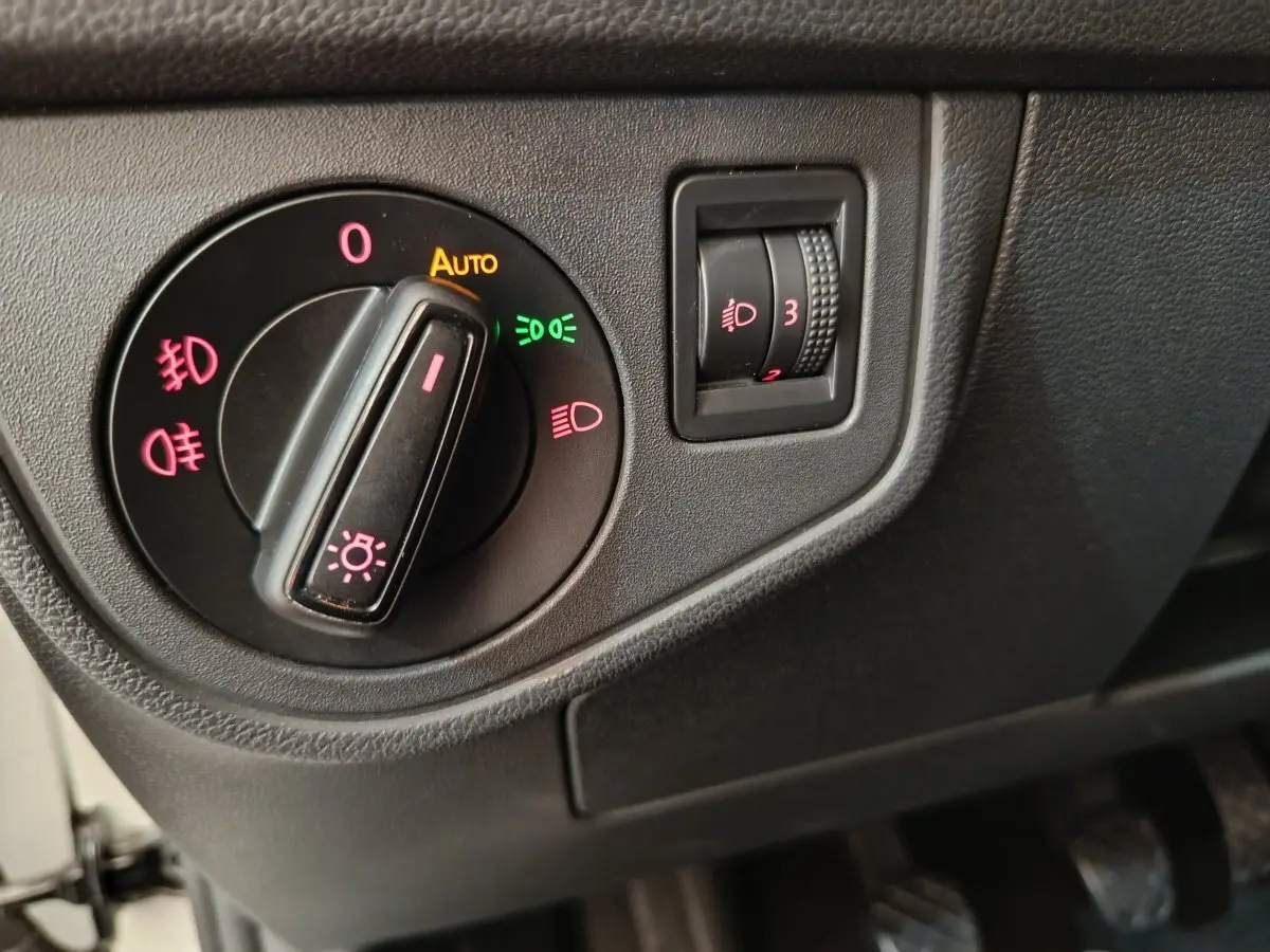 Gros plan sur les commandes d'éclairage noir mat du tableau de bord côté gauche de la Volkswagen Polo blanche 2020.