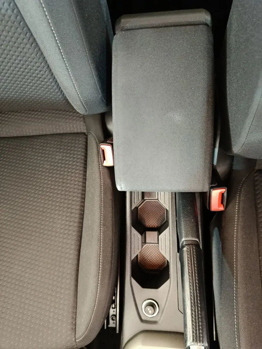 Vue plongeante sur la console centrale noire et les sièges tissu gris foncé de la Volkswagen Polo 2020 blanche.