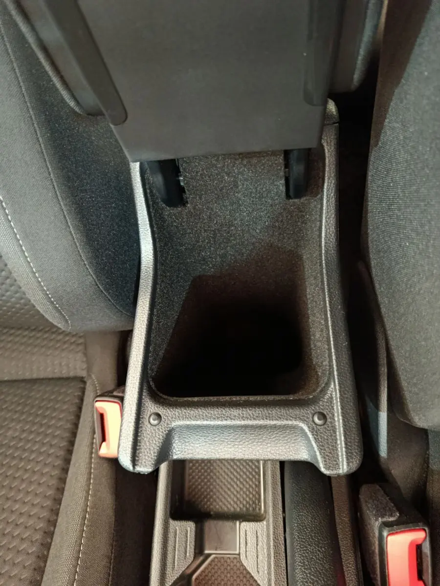 Vue rapprochée de la console centrale ouverte avec rangement noir entre les sièges avant d'une Volkswagen Polo blanche 2020.