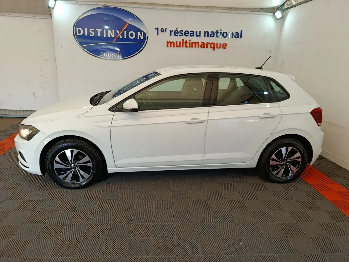 Profil côté gauche d'une Volkswagen Polo blanche 2020 en intérieur, avec jantes alliage et feux arrière visibles.