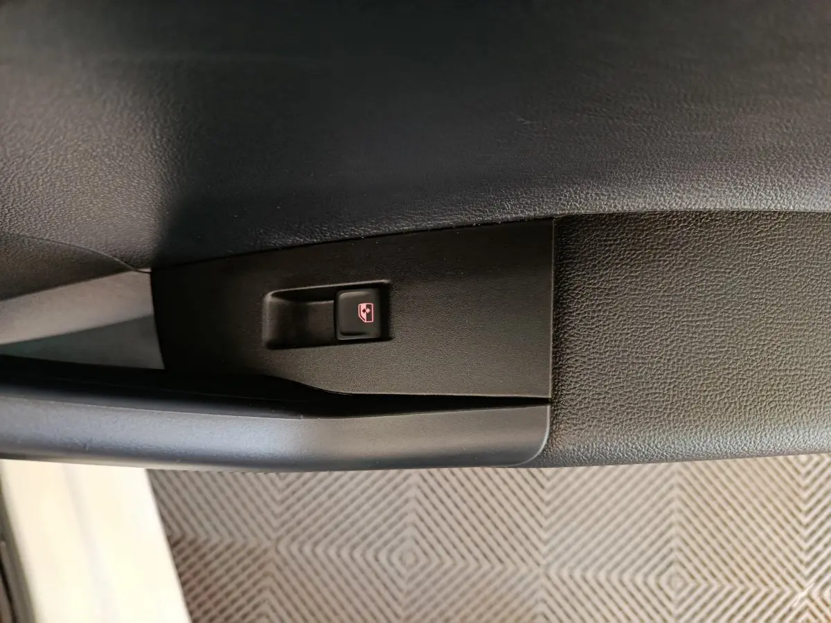 Gros plan sur le bouton de verrouillage centralisé noir dans la portière côté conducteur d'une Volkswagen Polo blanche 2020.