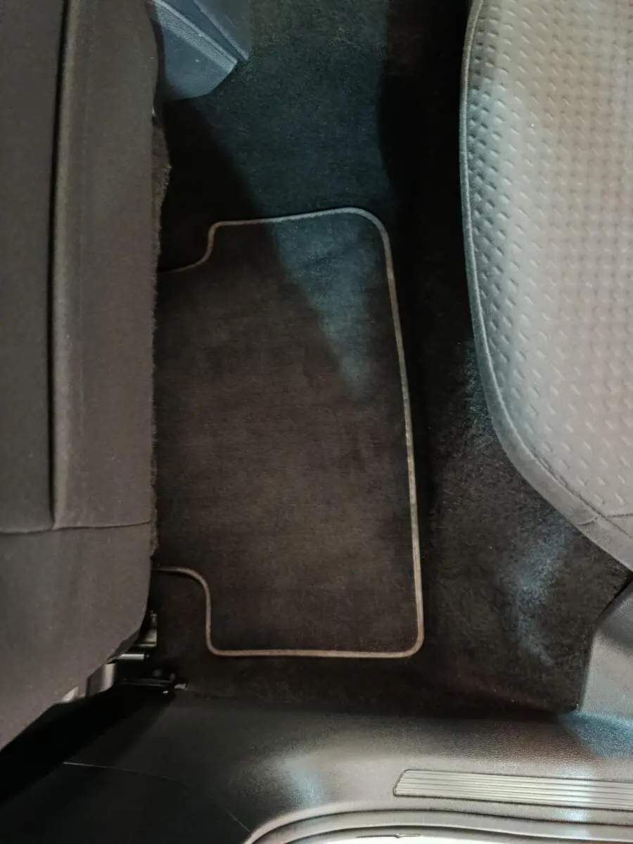 Vue rapprochée du tapis de sol noir et siège tissu gris côté droit arrière d'une Volkswagen Polo blanche 2020.