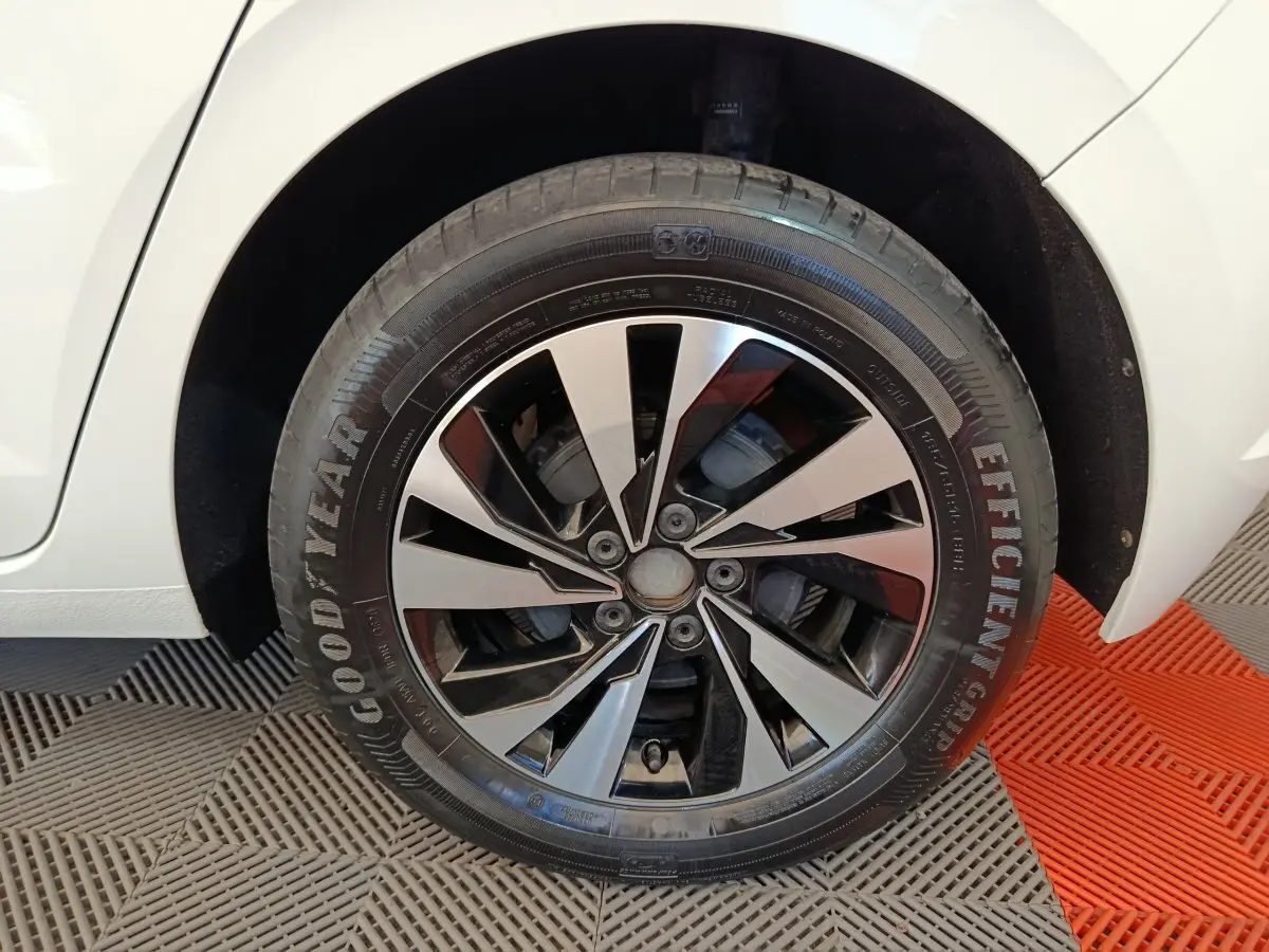 Gros plan sur la roue arrière droite d'une Volkswagen Polo blanche, avec partie de la carrosserie visible.