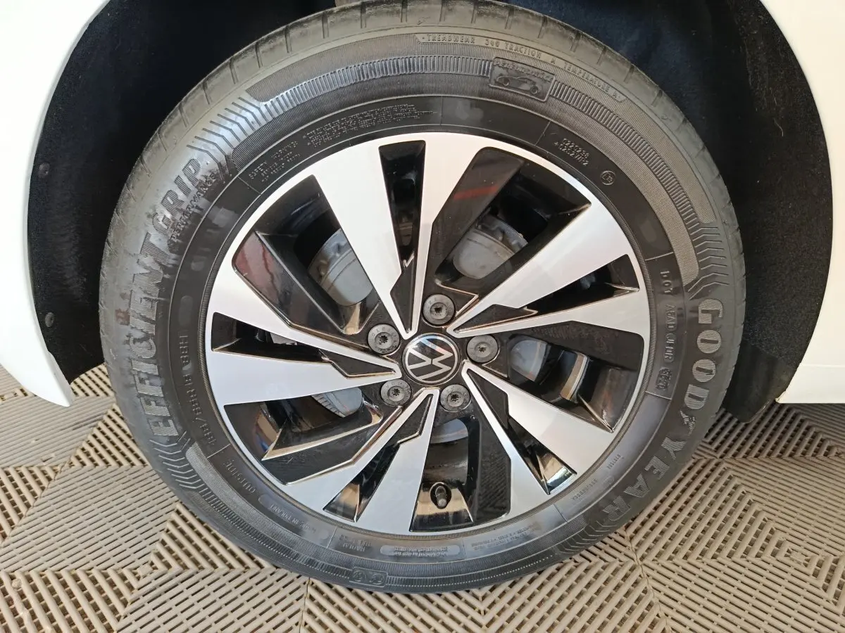 Gros plan sur la roue avant droite d'une Volkswagen Polo blanche avec jante alliage bicolore noir et argentée.