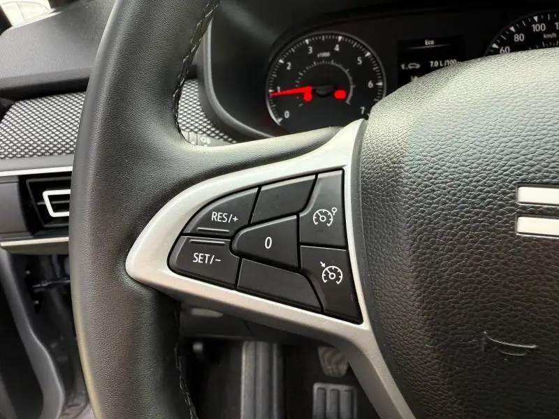 Gros plan sur les commandes au volant côté gauche du Dacia Jogger gris 2025, avec tableau de bord en arrière-plan.