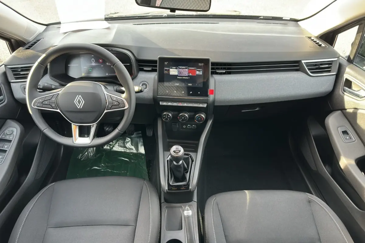 Vue intérieure avant de la Renault Clio DCI 100 Evolution Camera 2025, tableau de bord gris, volant cuir multifonctions et boîte manuelle.