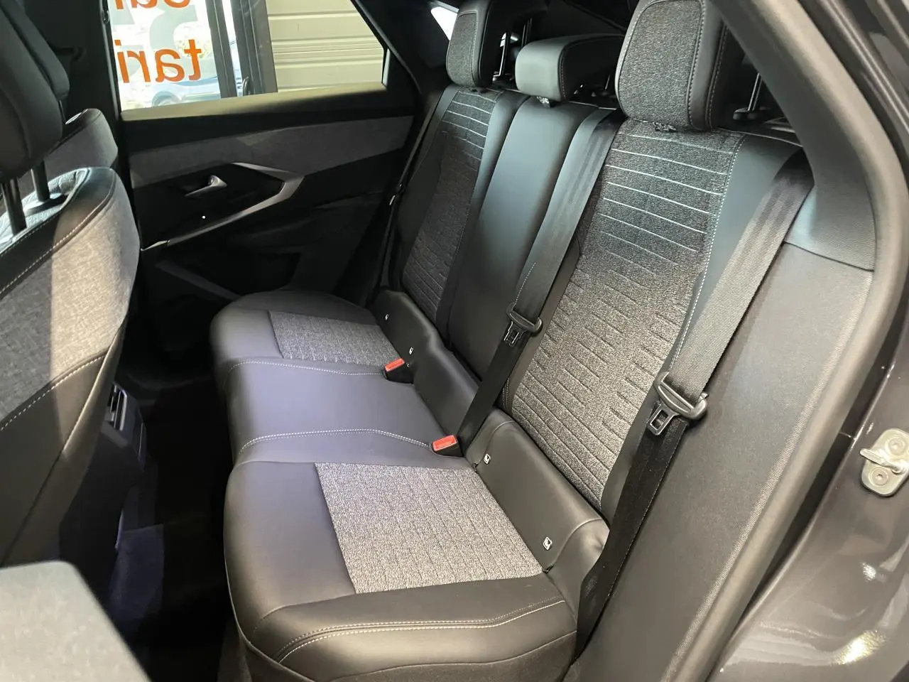 Vue intérieure côté droit sur la banquette arrière gris foncé et tissu chiné du Peugeot 3008 hybride 2025.