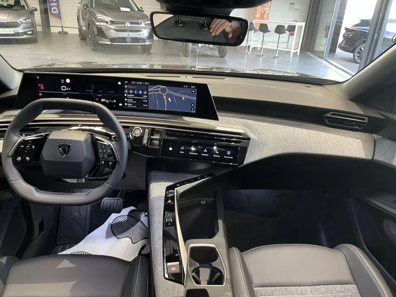 Vue intérieure du tableau de bord du Peugeot 3008 gris foncé 2025 avec écran incurvé et volant compact noir.