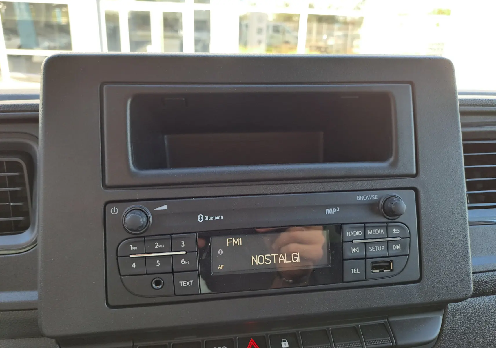 Vue rapprochée de la radio Bluetooth MP3 du tableau de bord du Nissan Interstar blanc, affichant la station FM1 NOSTALGI.