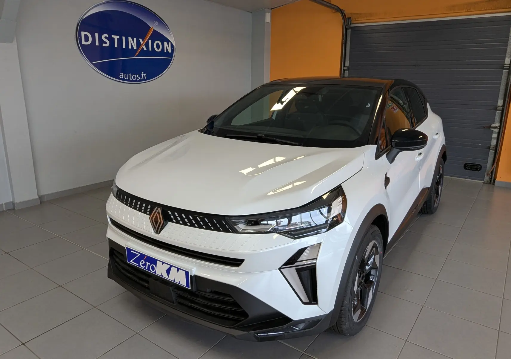 Renault Captur E-Tech hybride blanc nacré avec toit noir, vue 3/4 avant droit en intérieur showroom.
