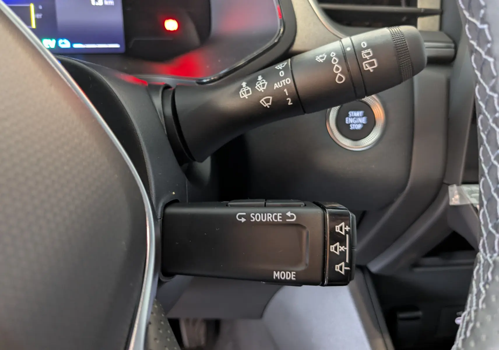 Gros plan sur la commande multifonction à gauche du volant du Renault Captur blanc nacré 2025 avec bouton start/stop visible.