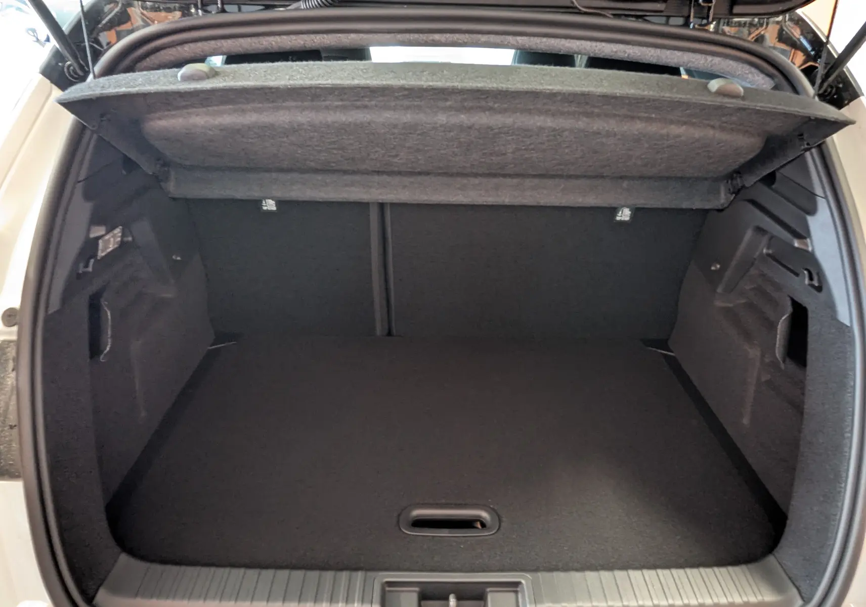 Coffre ouvert du Renault Captur E-Tech blanc nacré avec toit noir, vue arrière montrant l'espace de chargement vide.