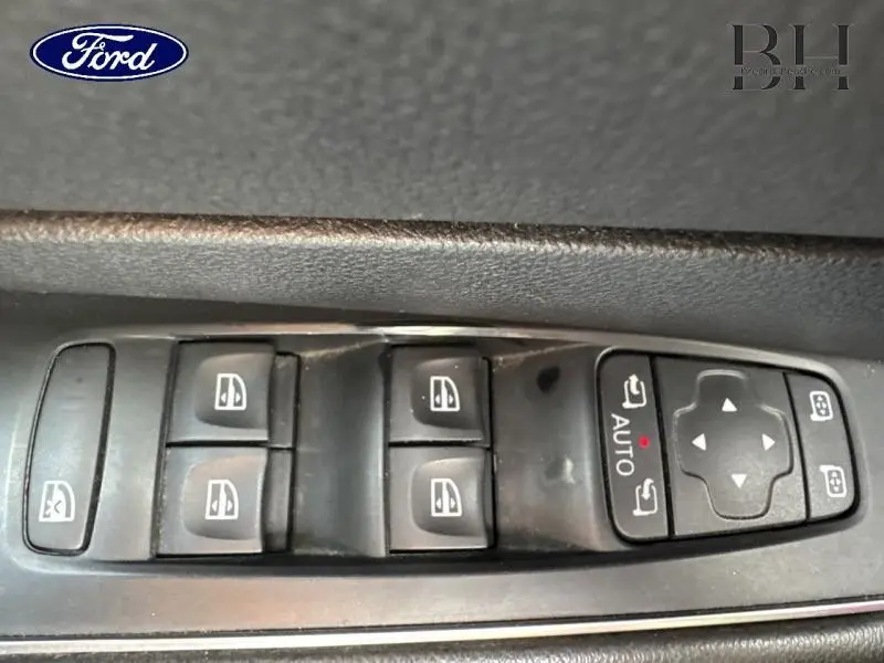 Panneau de commandes des vitres électriques et rétroviseurs sur la portière d'une Renault Talisman gris Cassiopée, vue rapprochée.