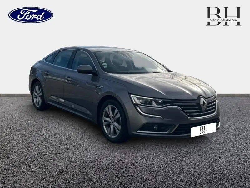 Renault Talisman gris Cassiopée en vue 3/4 avant droit, avec calandre distinctive et jantes alliage visibles.