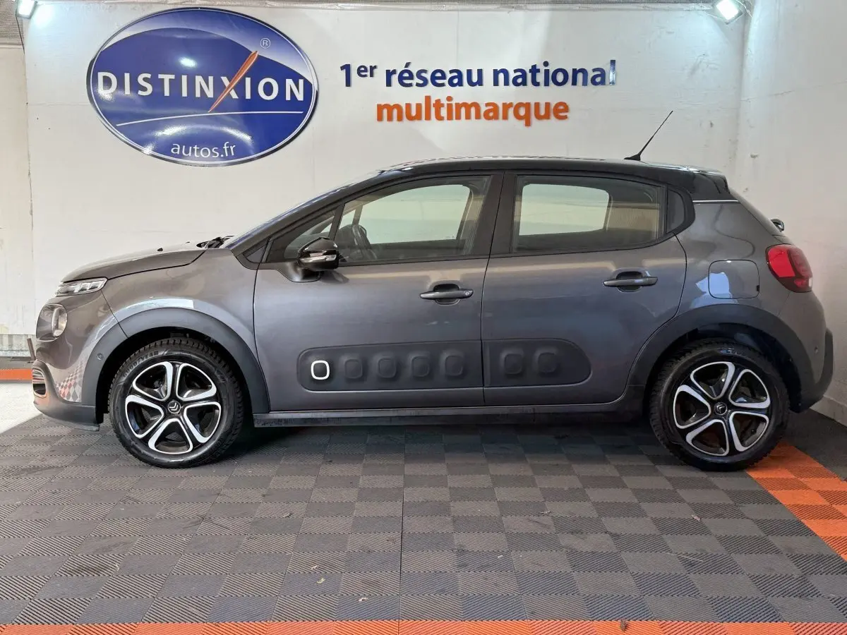 Profil côté gauche d'une Citroën C3 gris clair avec protections latérales noires et jantes alliage distinctives.