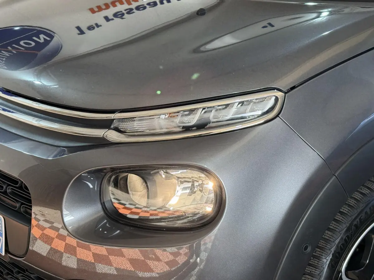 Gros plan sur le phare avant droit d'une Citroën C3 gris clair, mettant en valeur ses feux LED et la carrosserie lisse.