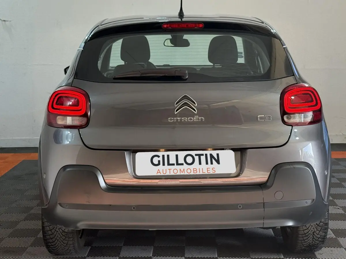 Vue arrière d'une Citroën C3 gris clair avec feux LED et logo centré sur le hayon dans un garage.