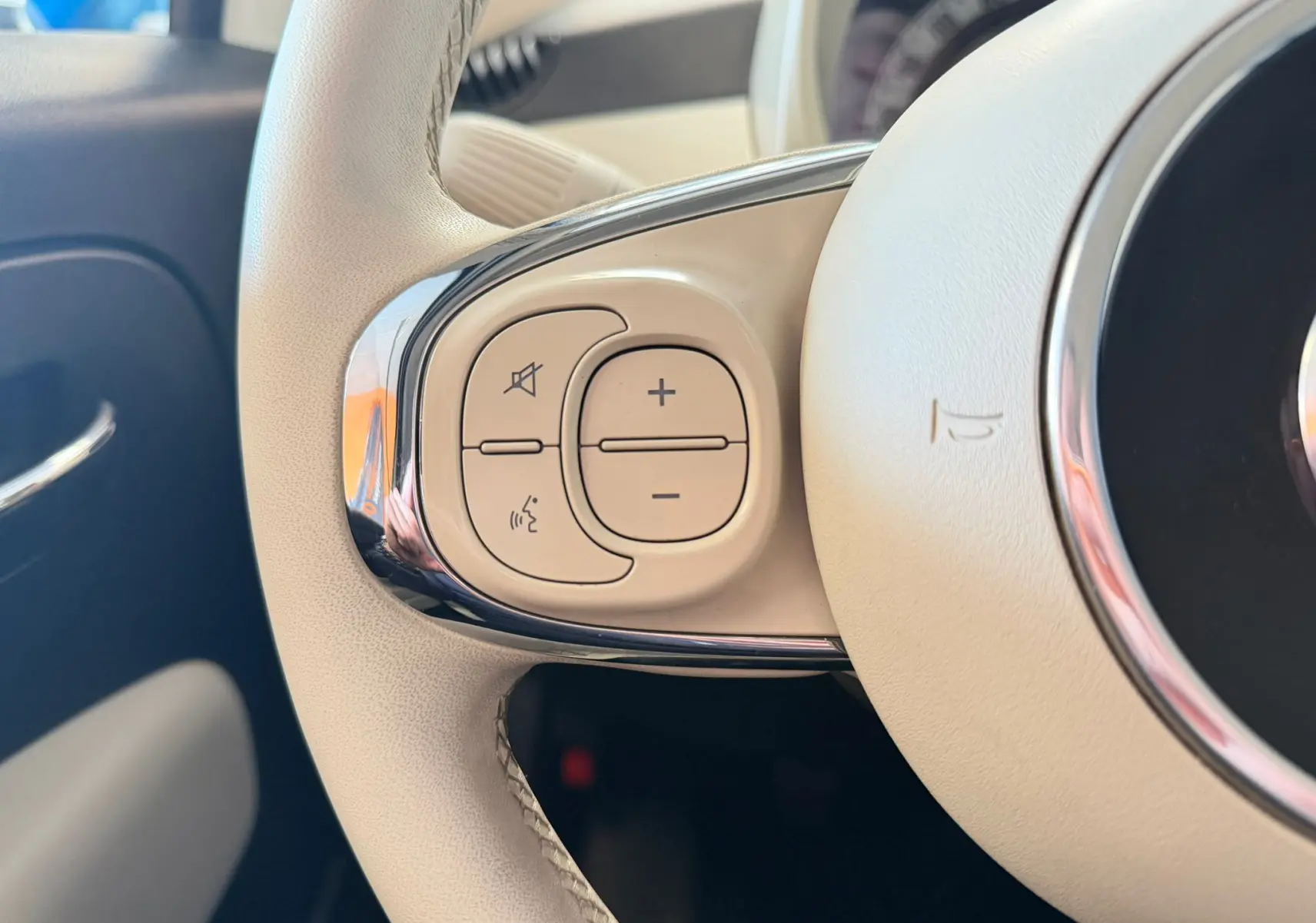 Gros plan sur les commandes gauche du volant beige clair de la FIAT 500 Dolcevita 2022 en Bossa Nova White.