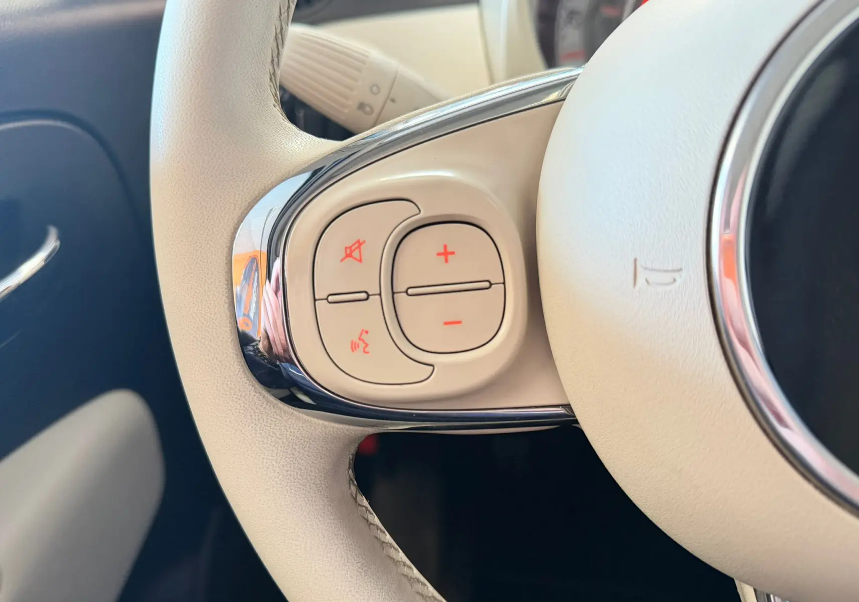 Gros plan sur les commandes gauche du volant beige clair de la Fiat 500 Dolcevita 2022 en Bossa Nova White.