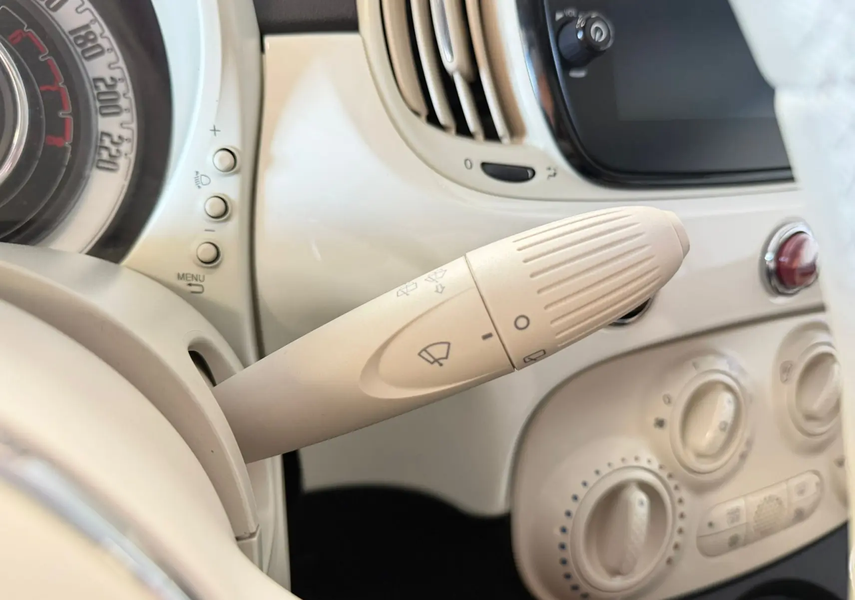 Gros plan sur la commande d'essuie-glace beige du tableau de bord de la Fiat 500 Dolcevita blanche, intérieur rétro.