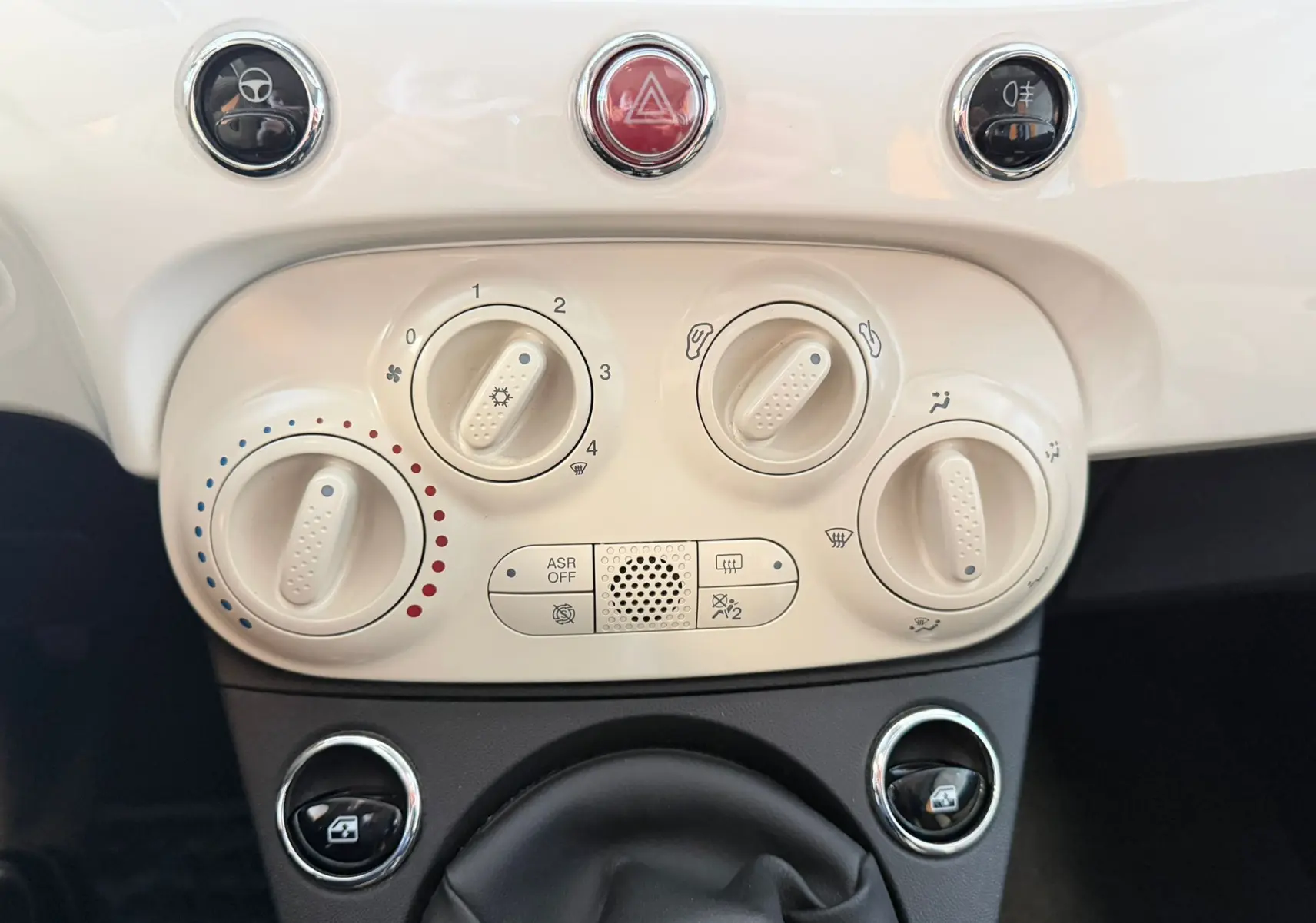 Vue rapprochée des commandes de climatisation et boutons de tableau de bord blanc cassé de la Fiat 500 Dolcevita 2022.