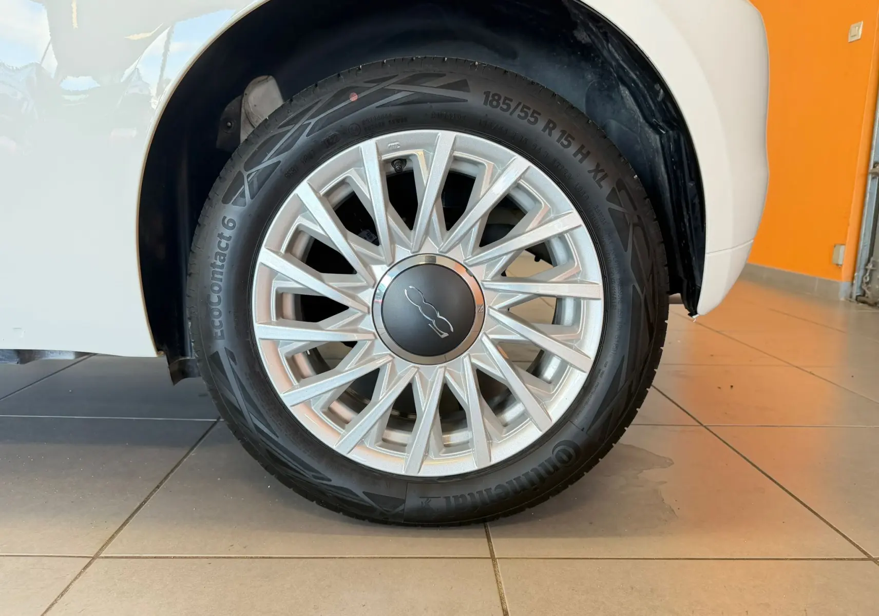 Gros plan sur la roue avant droite d'une FIAT 500 blanche Bossa Nova avec jante argentée au design étoilé.