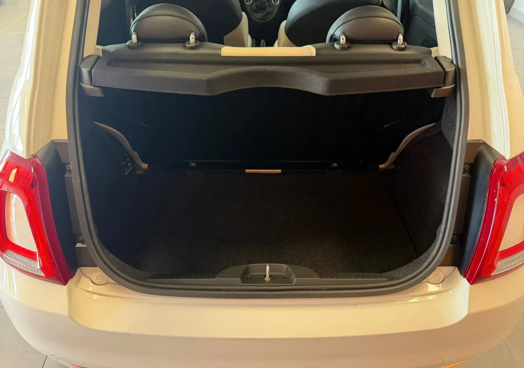 Coffre ouvert vu de l'arrière d'une Fiat 500 blanche Bossa Nova, montrant l'espace de chargement et les appuis-tête arrière.