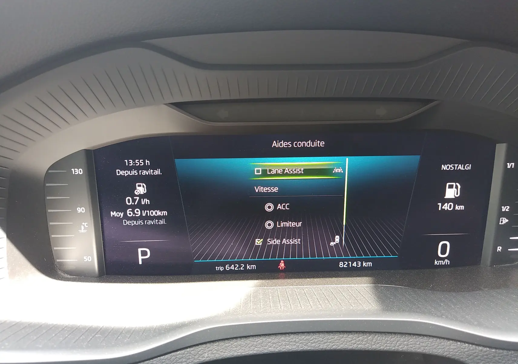 Affichage numérique du tableau de bord du Skoda Karoq gris, montrant les aides à la conduite et la consommation.
