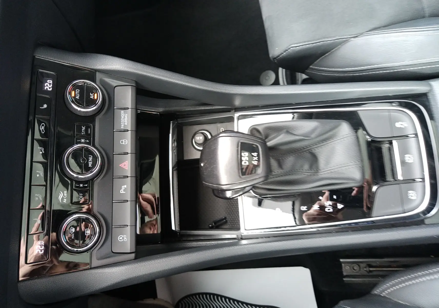 Vue plongeante sur la console centrale noire du Skoda Karoq gris, mettant en valeur le levier DSG 4x4 et les commandes de climatisation.