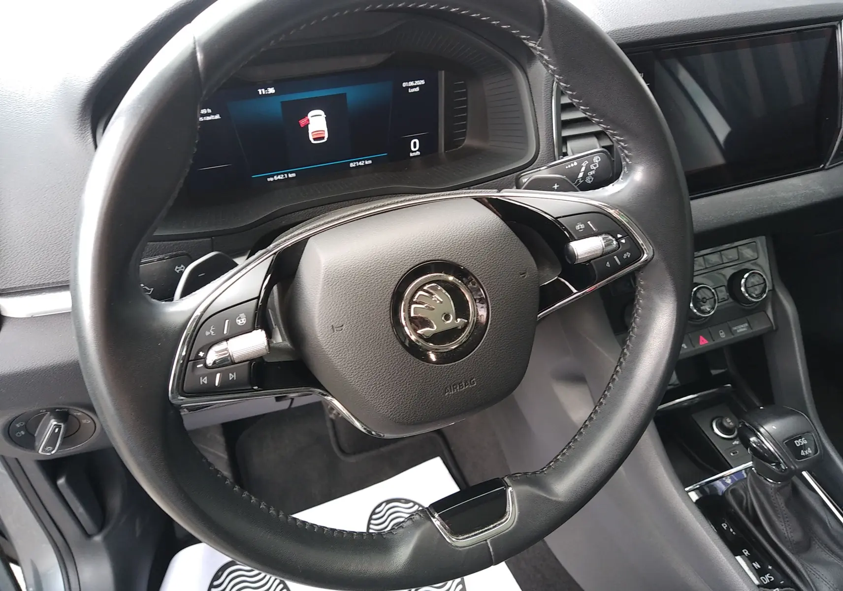 Vue intérieure centrée sur le volant noir de la Skoda Karoq 2022 avec tableau de bord numérique et levier DSG.
