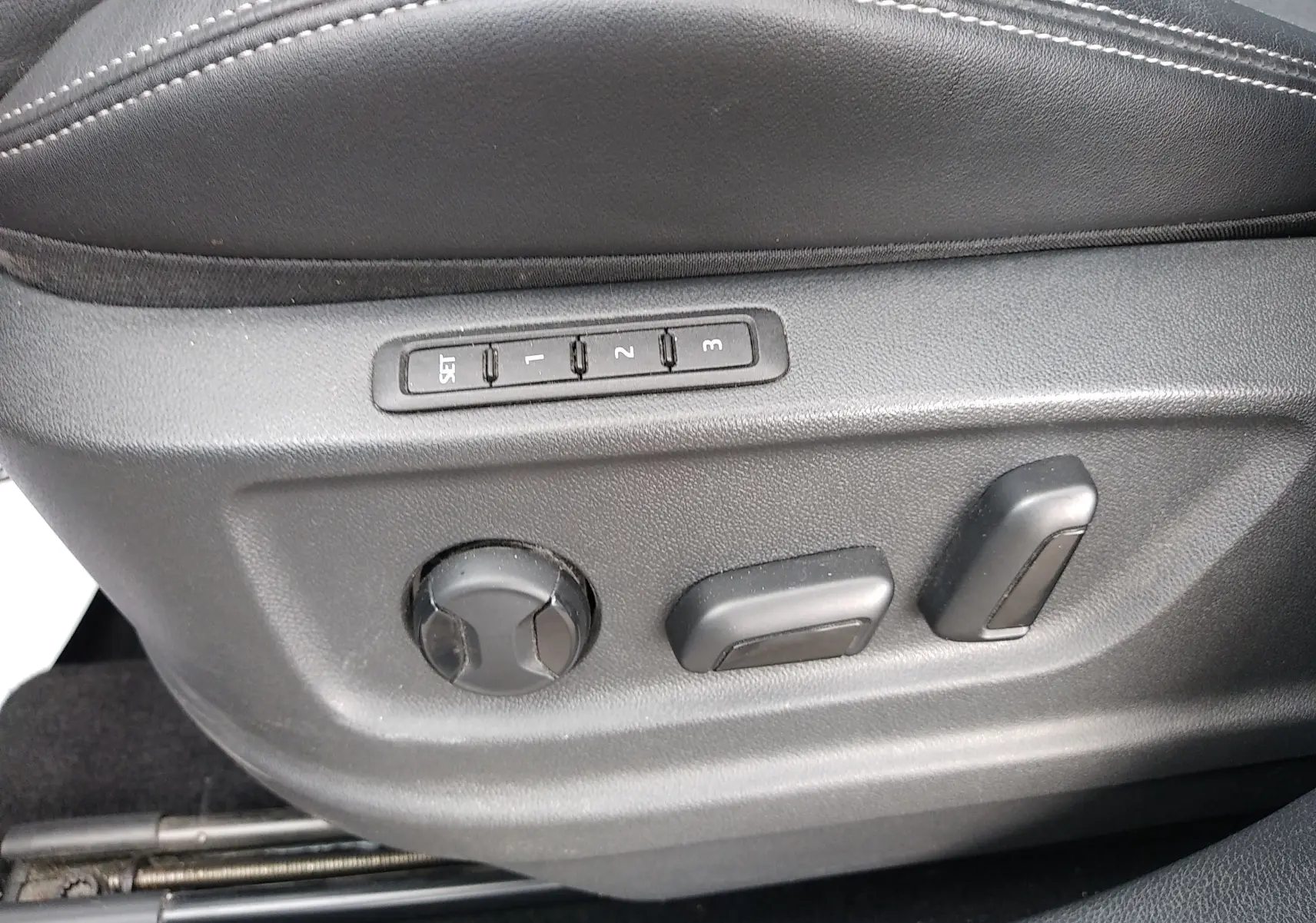 Gros plan sur les commandes de réglage électrique du siège conducteur en cuir noir du Skoda Karoq gris 2022.