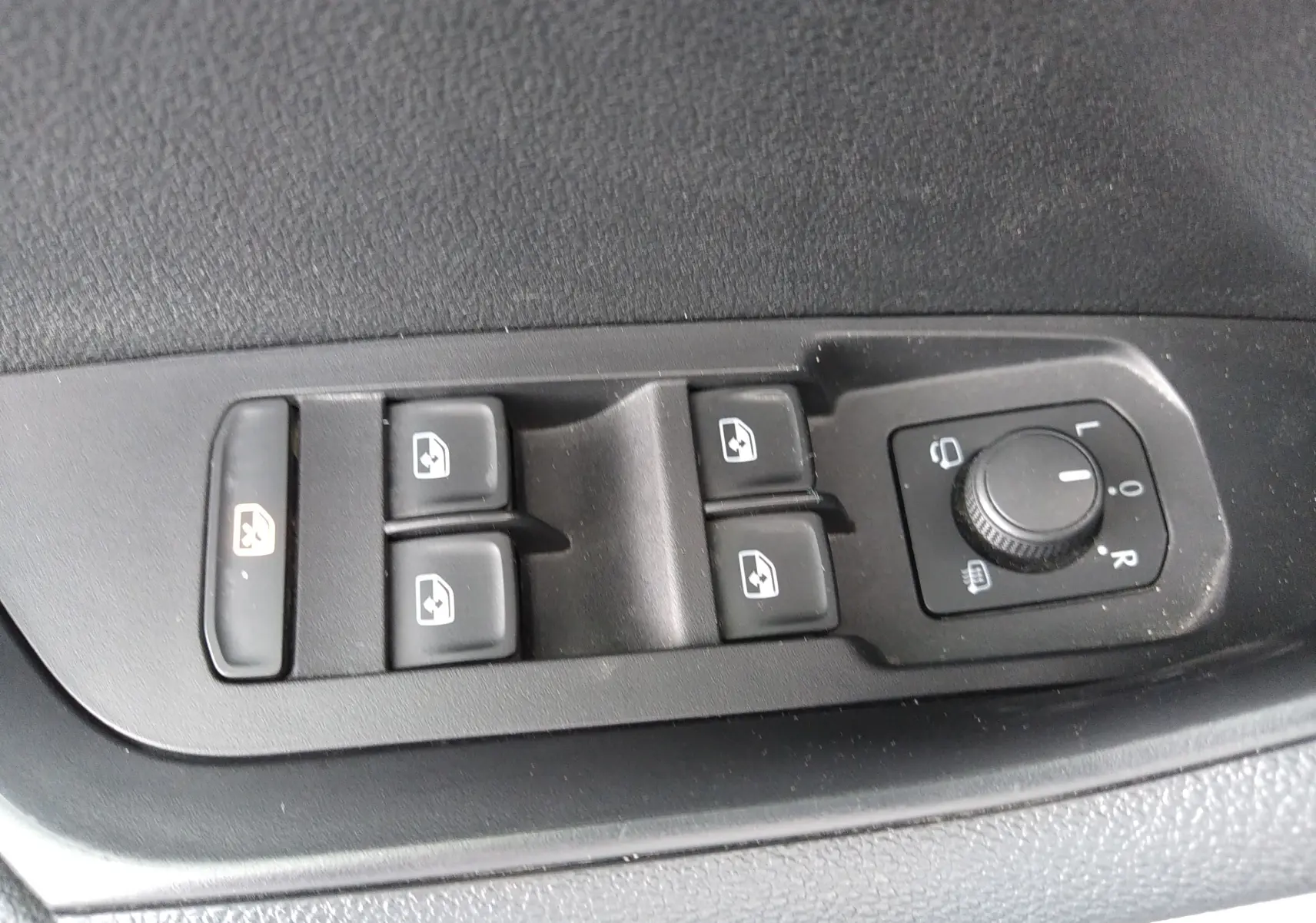 Gros plan sur les commandes de lève-vitres et réglage des rétroviseurs côté conducteur d'un Skoda Karoq gris 2022.