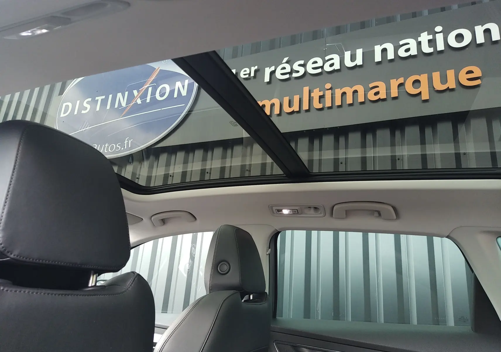 Vue intérieure du SKODA KAROQ gris 2022, mettant en valeur le toit panoramique et les sièges en cuir noir.