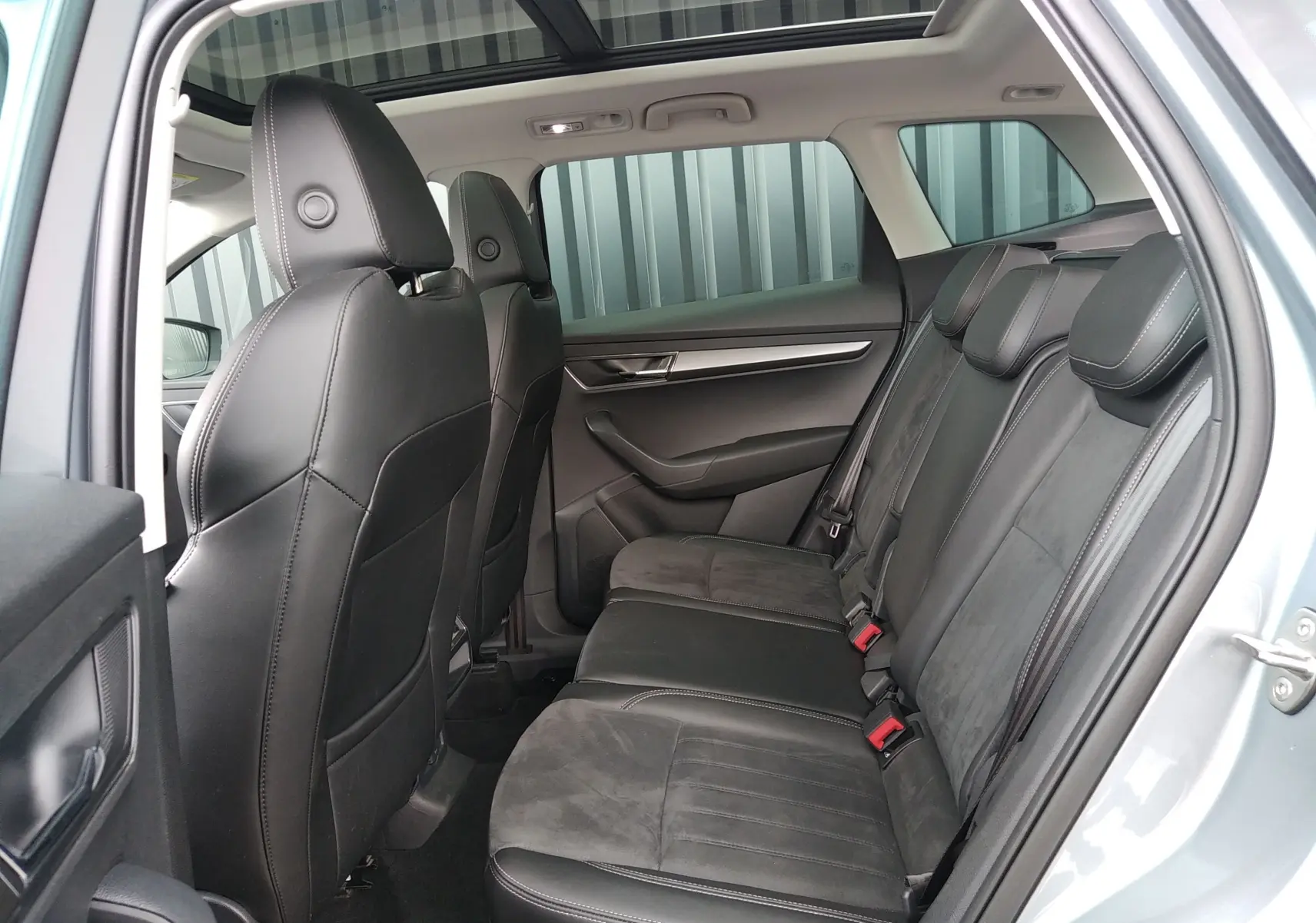 Vue intérieure côté droit des sièges arrière en cuir noir et alcantara du Skoda Karoq gris 2022 avec toit ouvrant panoramique.