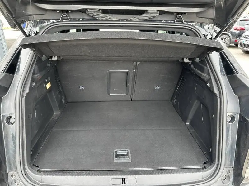 Coffre ouvert vu de l'arrière d'un Peugeot 3008 Hybride Rechargeable noir Perla Nera, espace de chargement vide et propre.