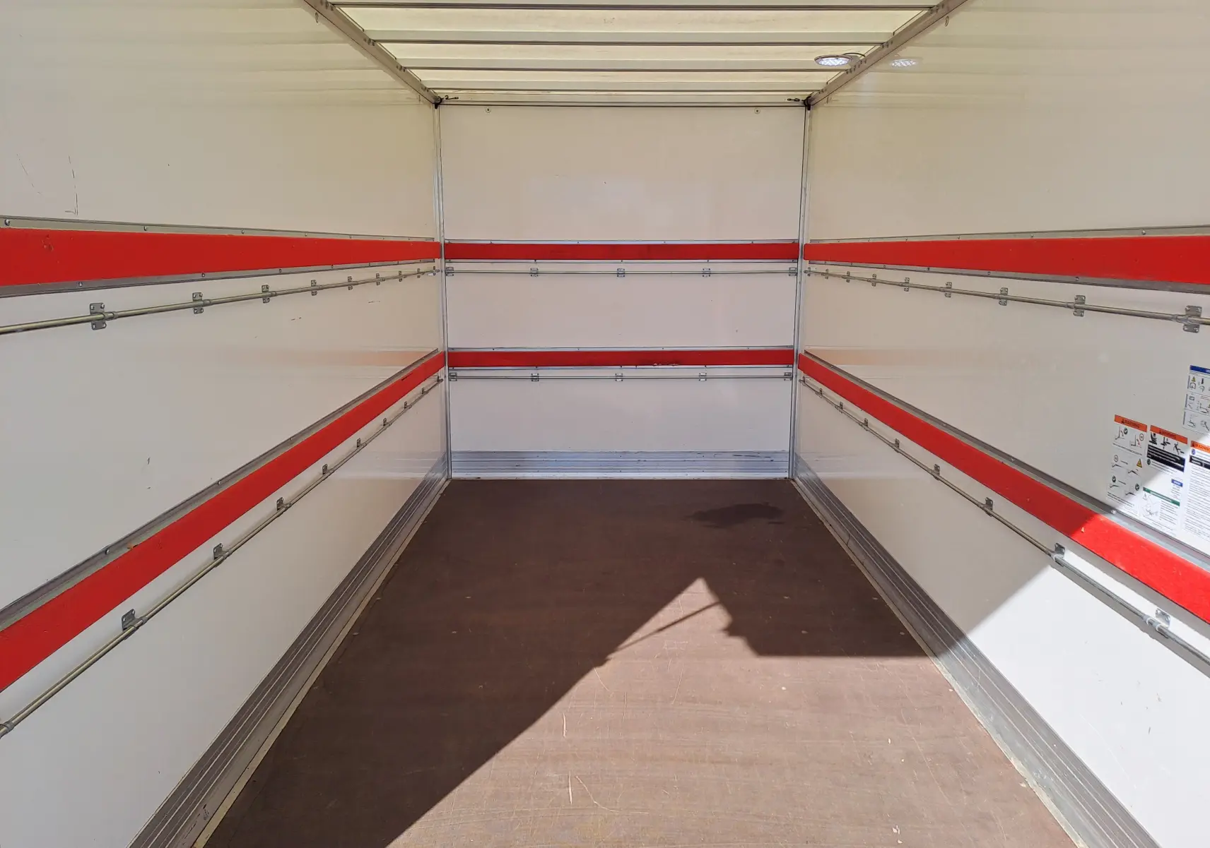 Intérieur vide du coffre du Nissan Interstar Chassis Cabine blanc, vue de l'arrière avec bandes rouges et rails métalliques.