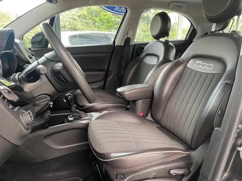 Vue intérieure côté conducteur de la FIAT 500X noire, sièges en cuir avec logo 500 brodé et volant multifonction.