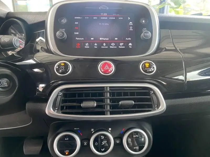 Tableau de bord noir brillant de la Fiat 500X 2018 avec écran tactile central et commandes climatisation circulaires.