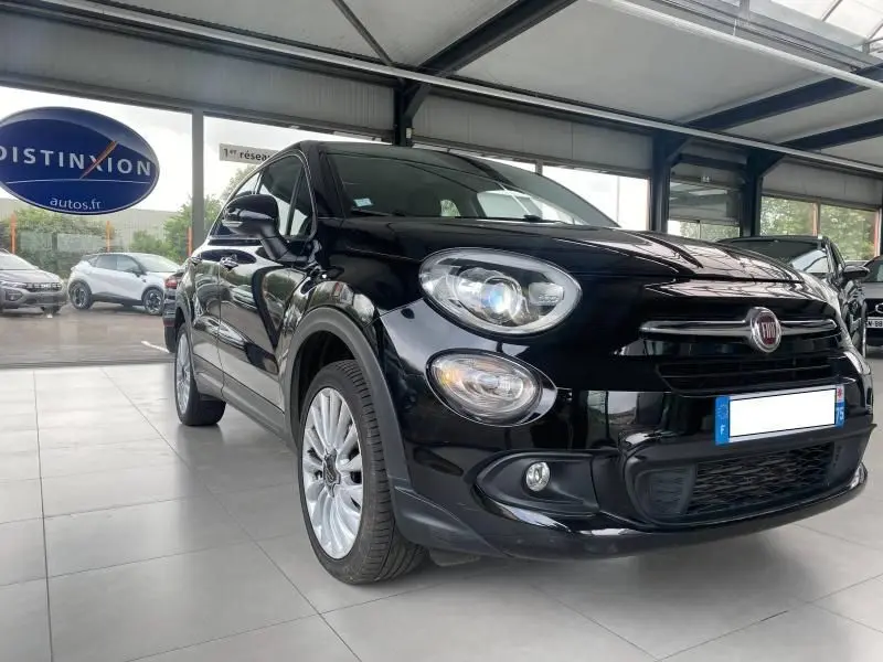 Vue 3/4 avant droite d'une FIAT 500X noire 2018 avec phares xénon et jantes alliage dans un showroom.