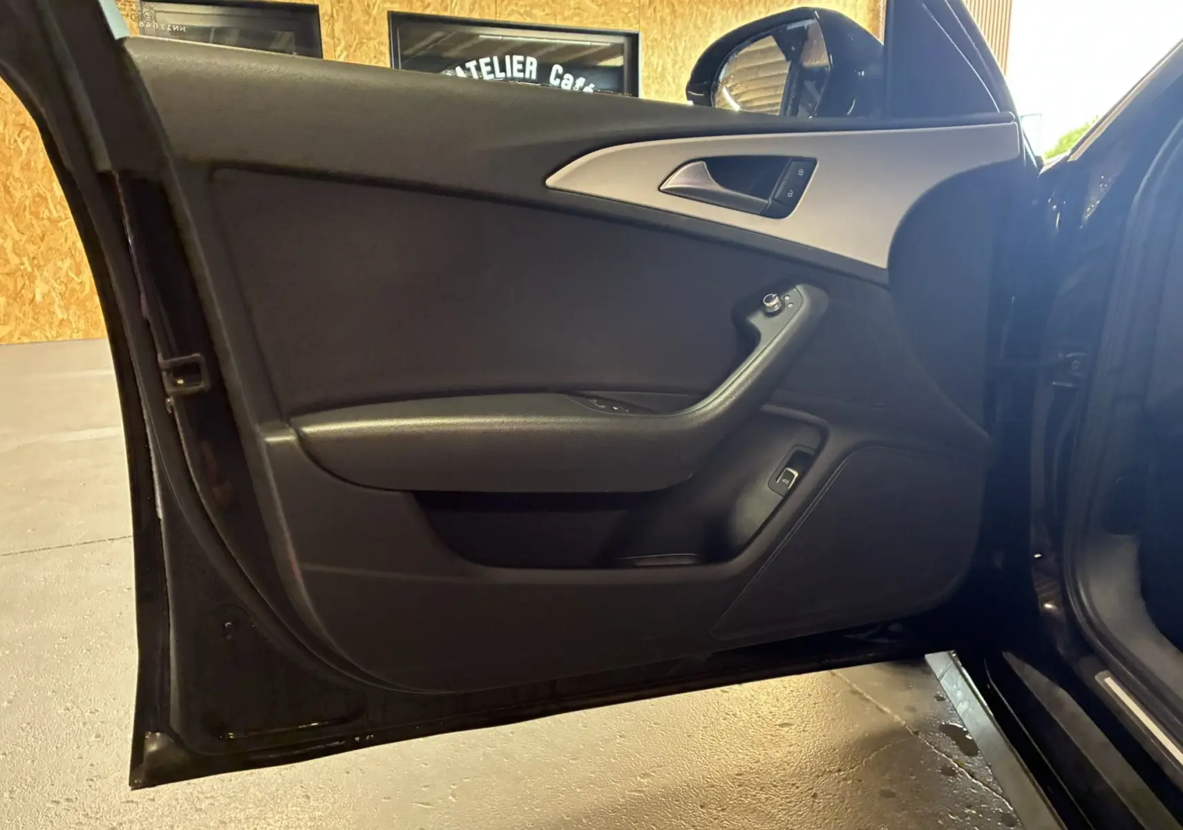 Vue intérieure de la porte avant gauche noire de l'Audi A6 Avant 2.0 TDI 2017 avec habillage tissu et commandes électriques.